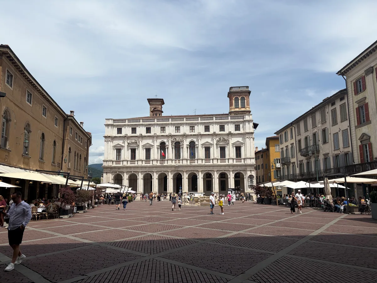 Die Piazza Vecchia in Bergamos, mit dem Palazzo Nuovo, beherbergt eine der bedeutensten historischen Bibliotheken Italiens. Ein grosser Platz mit rötlichen Pflastersteinen umrahmt von Renaissance-Palazzi.