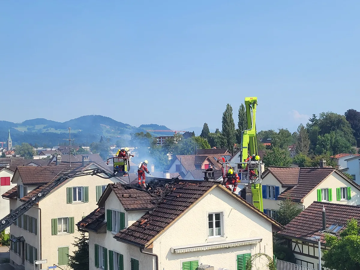 Feuerwehrmänner auf einem brennendem Dach.