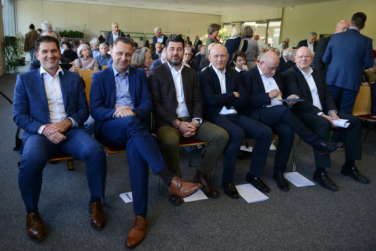 Die Stimmung der Aktionäre war zur Freude des Verwaltungsrats und trotz gewissen negativen Ergebnissen äusserst positiv. Männer sitzen in Anzügen auf Stühlen in einem Saal und schauen in die Kamera.