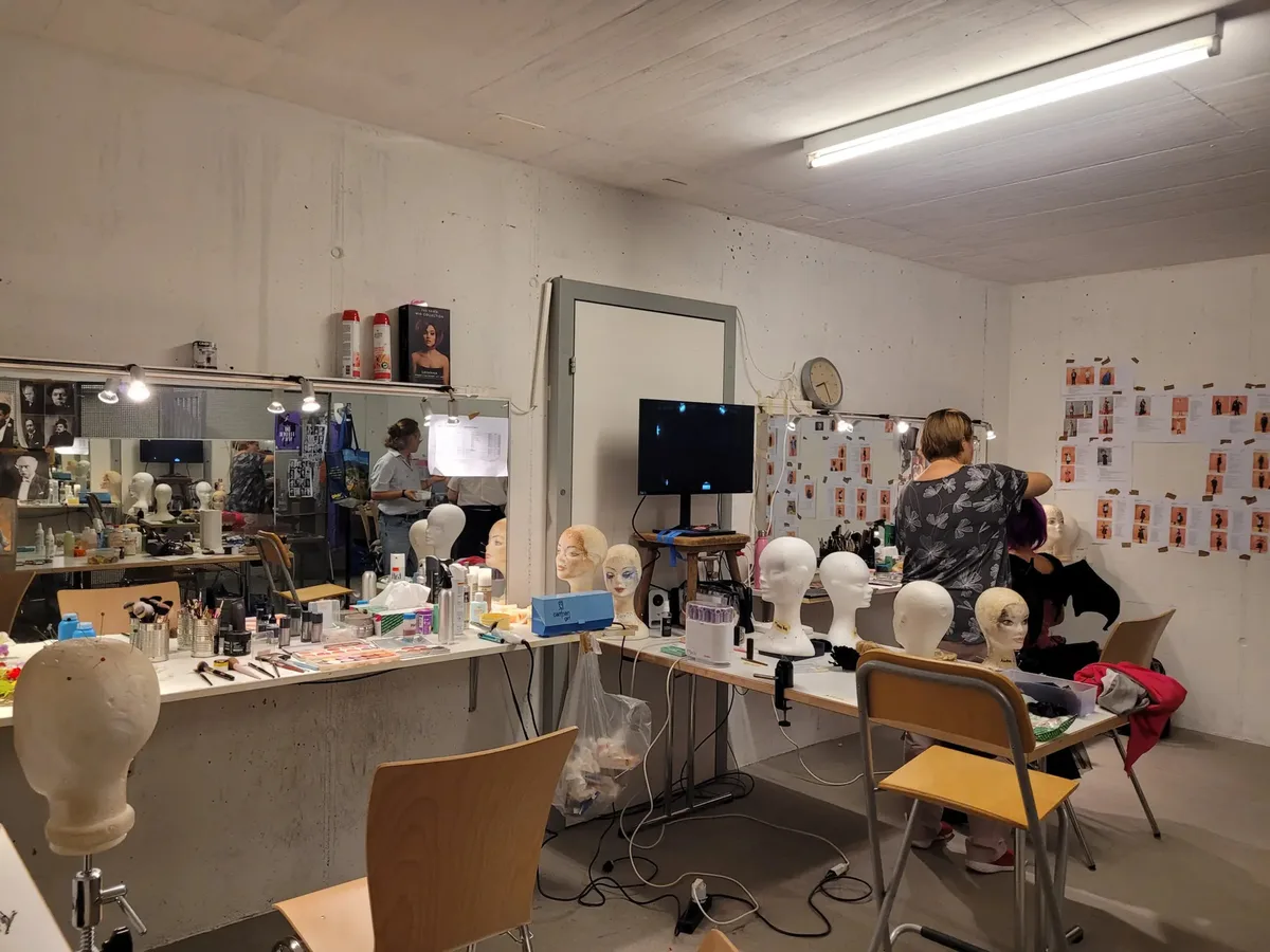Man sieht einen Raum, indem die Schauspieler geschminkt werden.