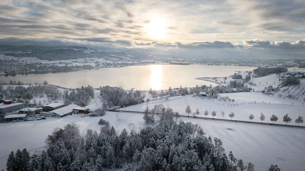 Ein See in verschneiter Landschaft.