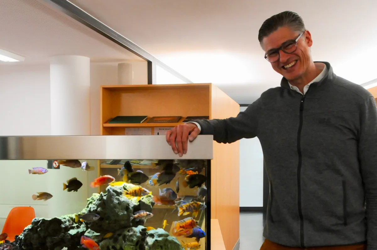 Man sieht einen Arzt in seiner Praxis neben einem Aquarium.