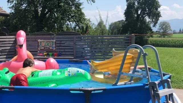 Man sieht ein Kind auf einer Luftmatratze im Garten-Pool.