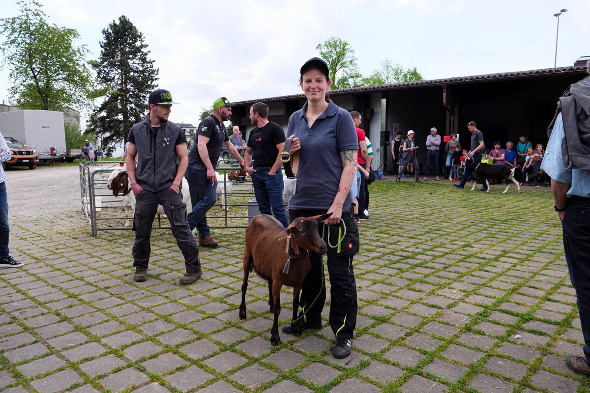 Eine Ziegenhalterin posiert mit einer braunen Ziege.