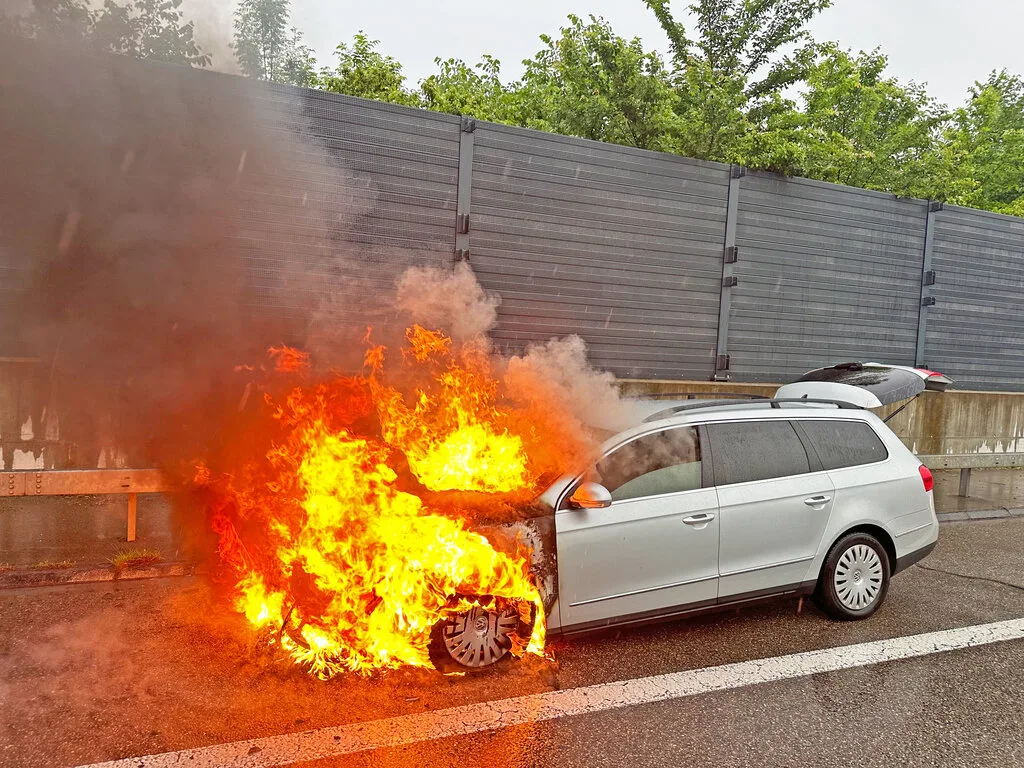 Ein Auto brennt auf der Autobahn, die Feuerwehr löscht den Brand. Ein Auto brennt auf der Autobahn, die Feuerwehr löscht den Brand.
