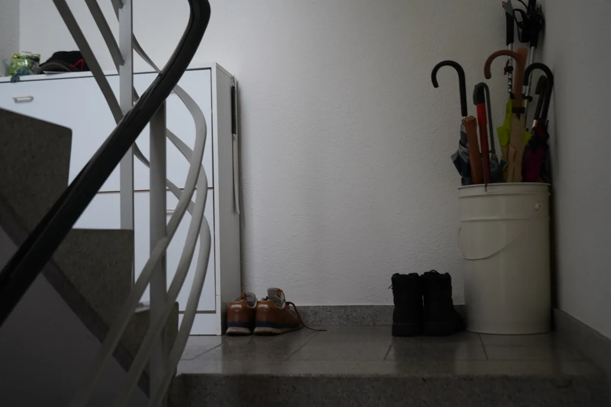 Im Treppenhaus: eine Kommode, ein Schirmständer und Schuhe.