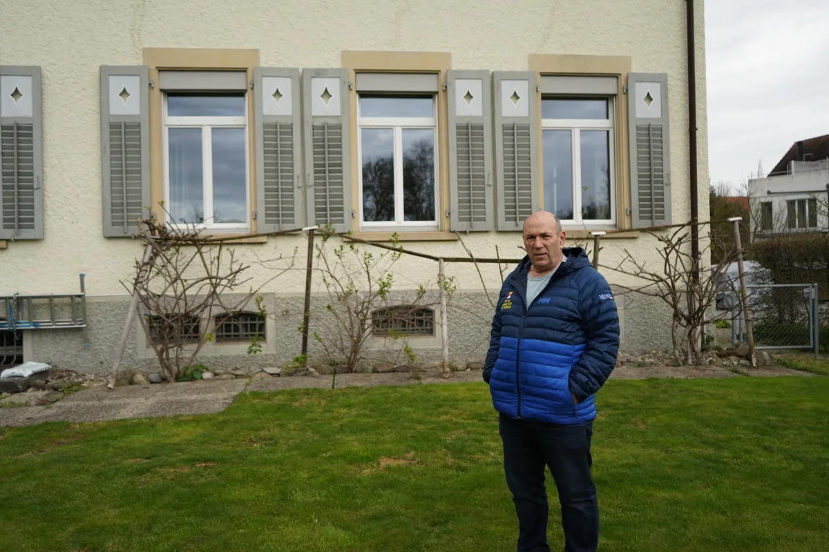 Armin Lanz steht in einem Garten vor dem Saal der Reformierten Kirche.