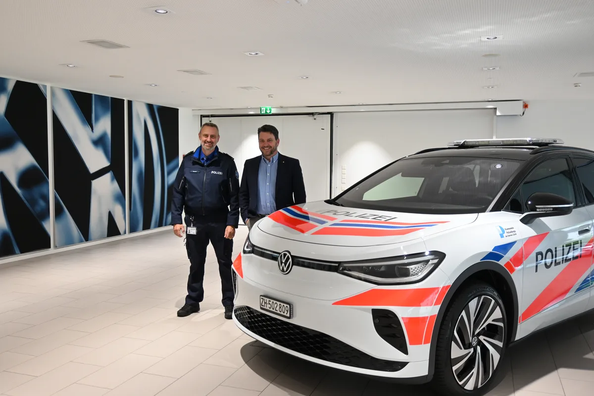 Zwei Männer stehen neben einem Polizeifahrzeug.