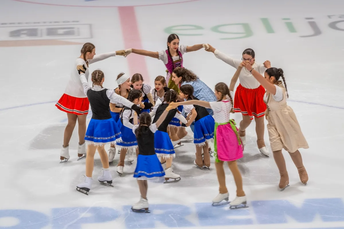 Ein äusserer und ein innerer Kreis an Eiskunstläuferinnen in traditionellerem Schweizerkostüm.