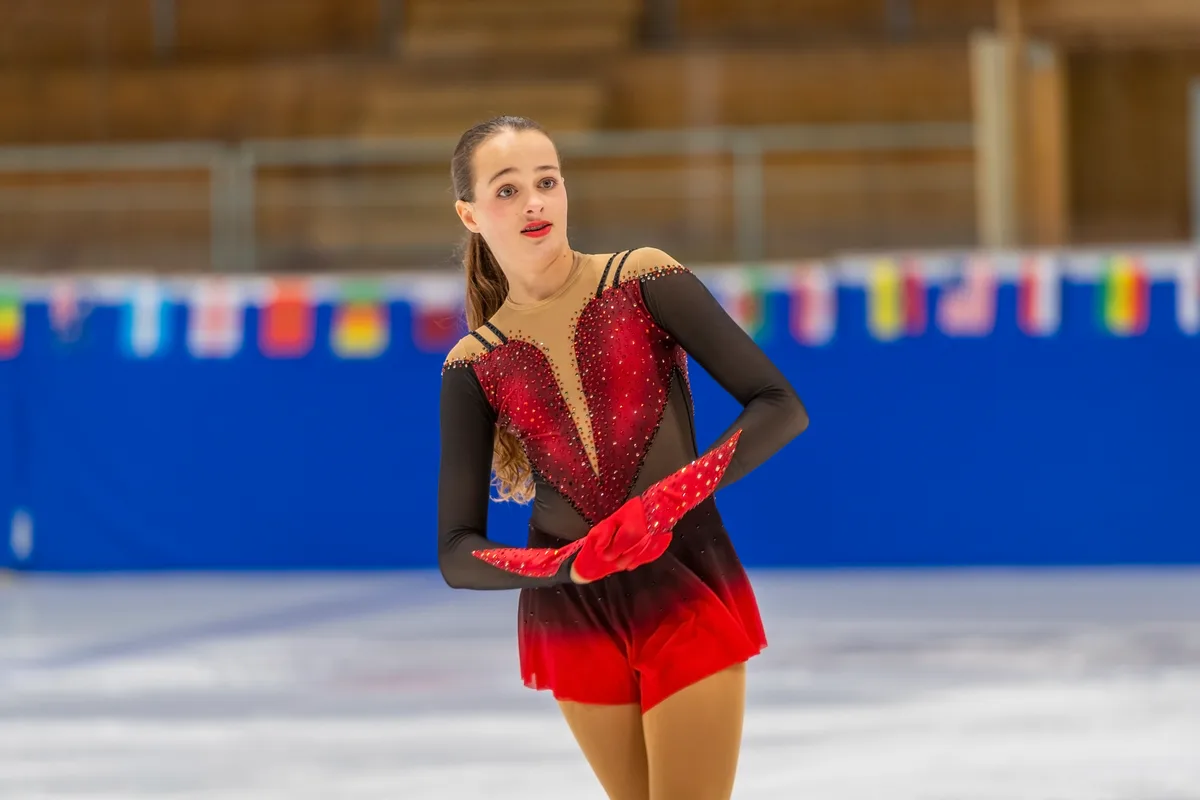 Delia in Nahaufnahme auf dem Eis. Sie trägt ein rotes Kostüm.