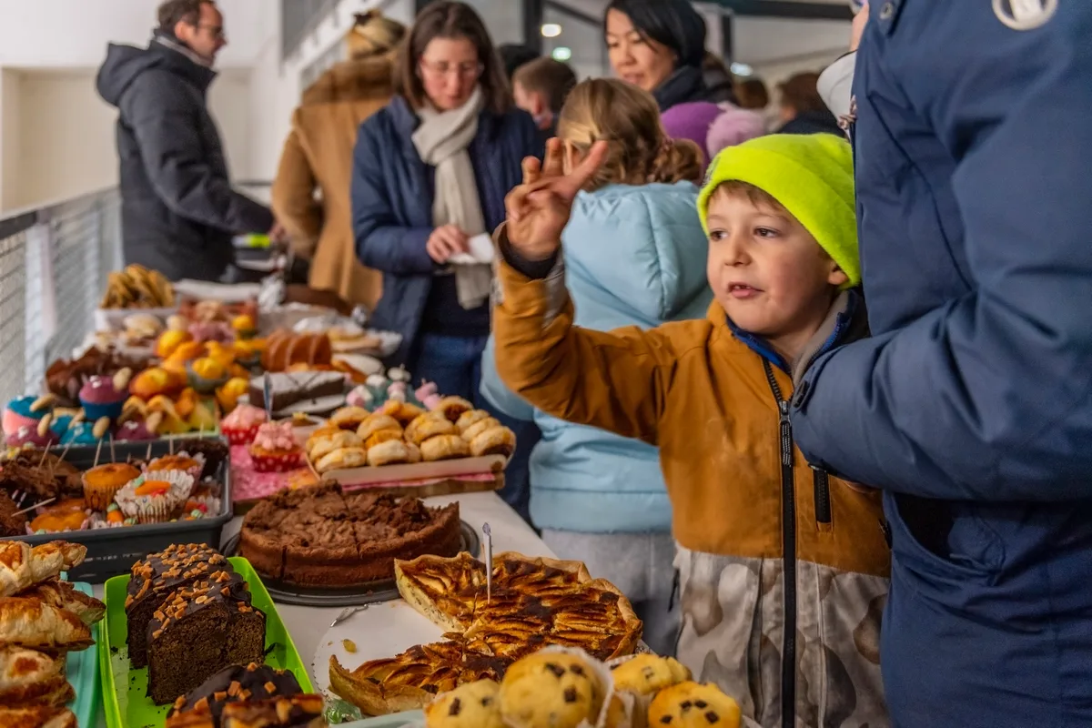 Menschen, die vor einem reichhaltigen Buffet mit Kuchen, Wähen und Muffins stehen.