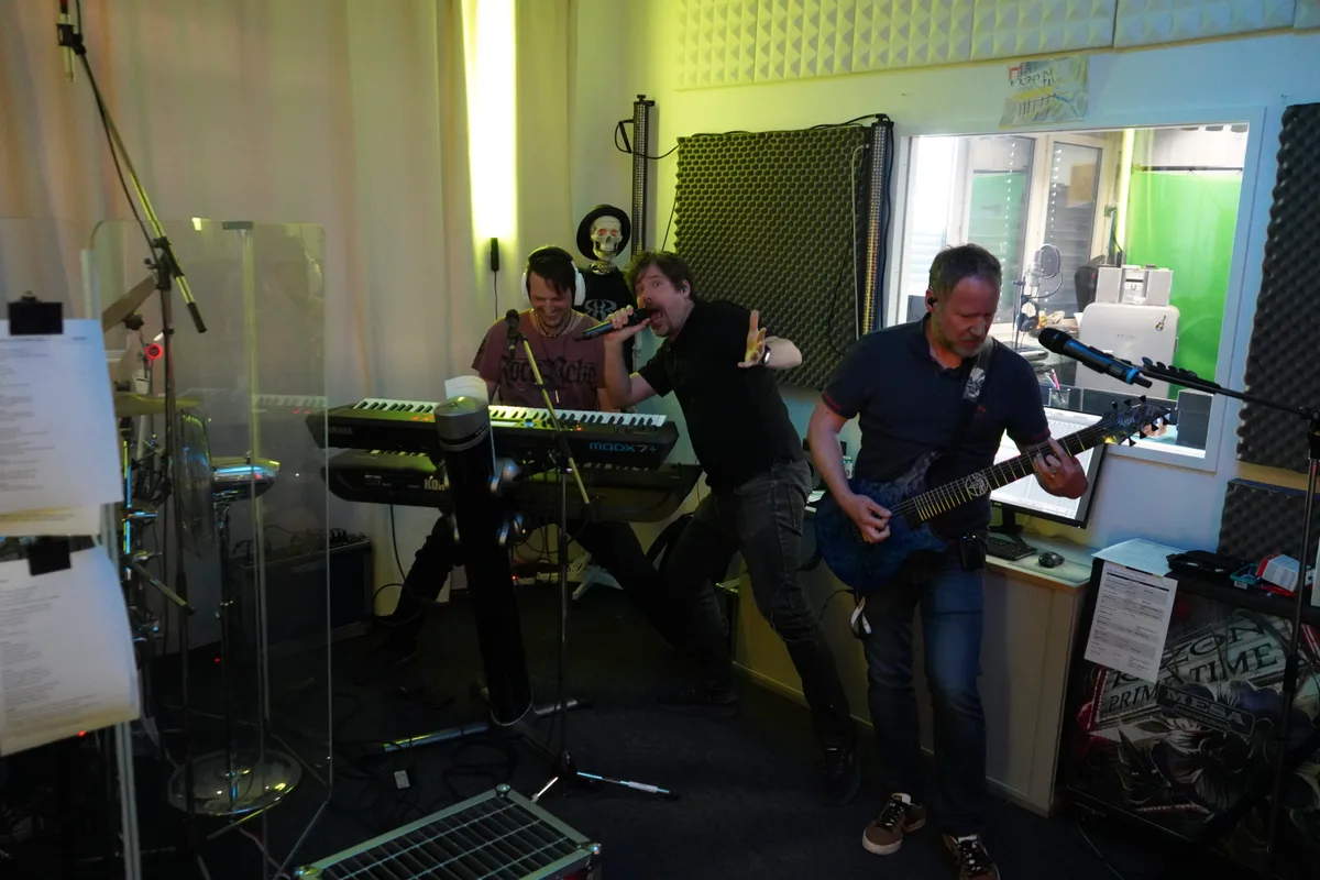 Marco Küderli, Matt Götz und Chris Götz (v.l.) wollten cool sein und gründeten in jungem Alter eine Band. Die gemeinsame Leidenschaft ist bis heute geblieben. Man sieht drei Männer in einem Proberaum. Einer sitzt am Keyboard, einer singt und einer spielt Gitarre.