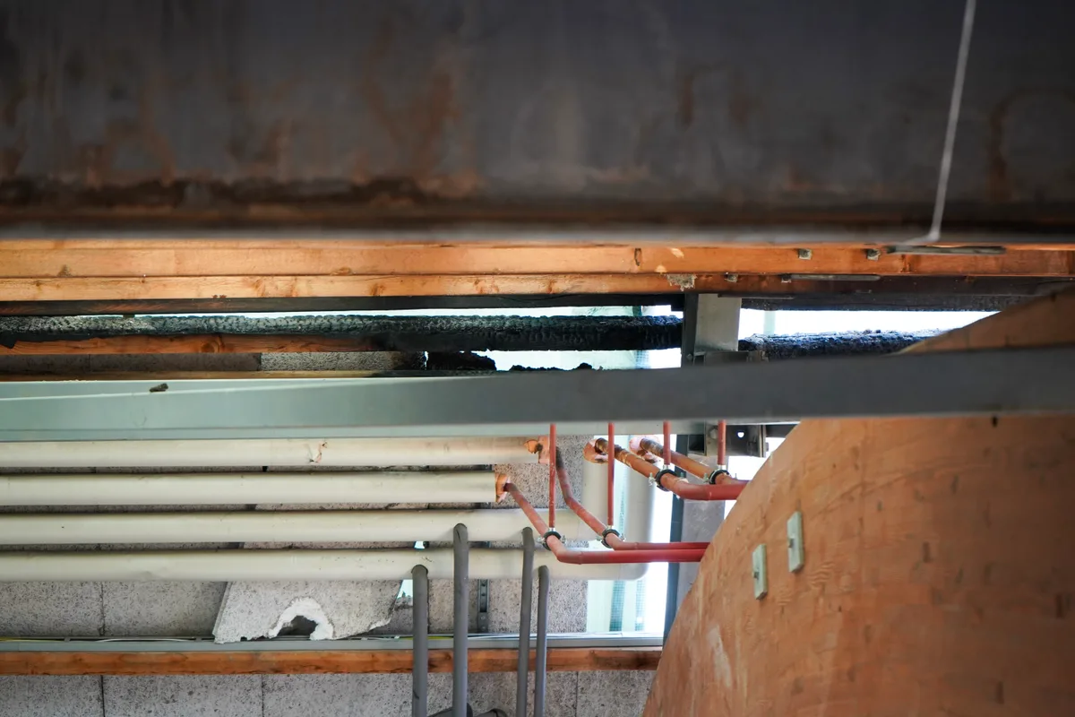 Zwischen Leitungen sieht man verkohlte Holzbalken.