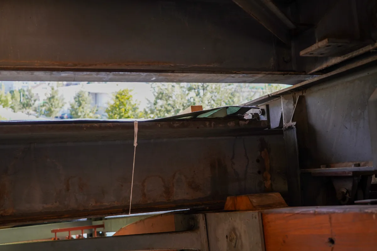 Man sieht, wie eine Blache mit einer Schnur provisorisch an einem Balken befestigt ist.