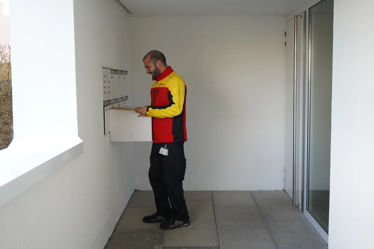 Emre Yaylan steckt ein Paket in einen Briefkasten.
