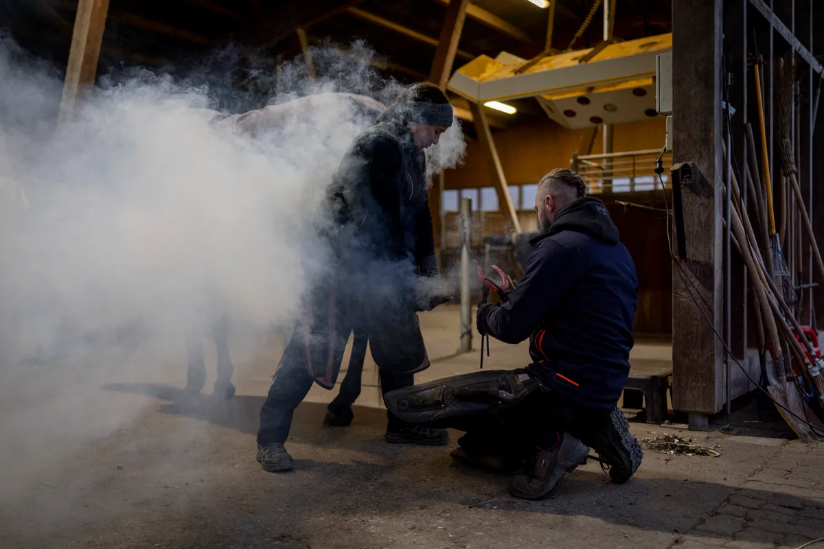 Rona Jimmy hält den Huf, und Juraj Hodas richtet das Eisen.