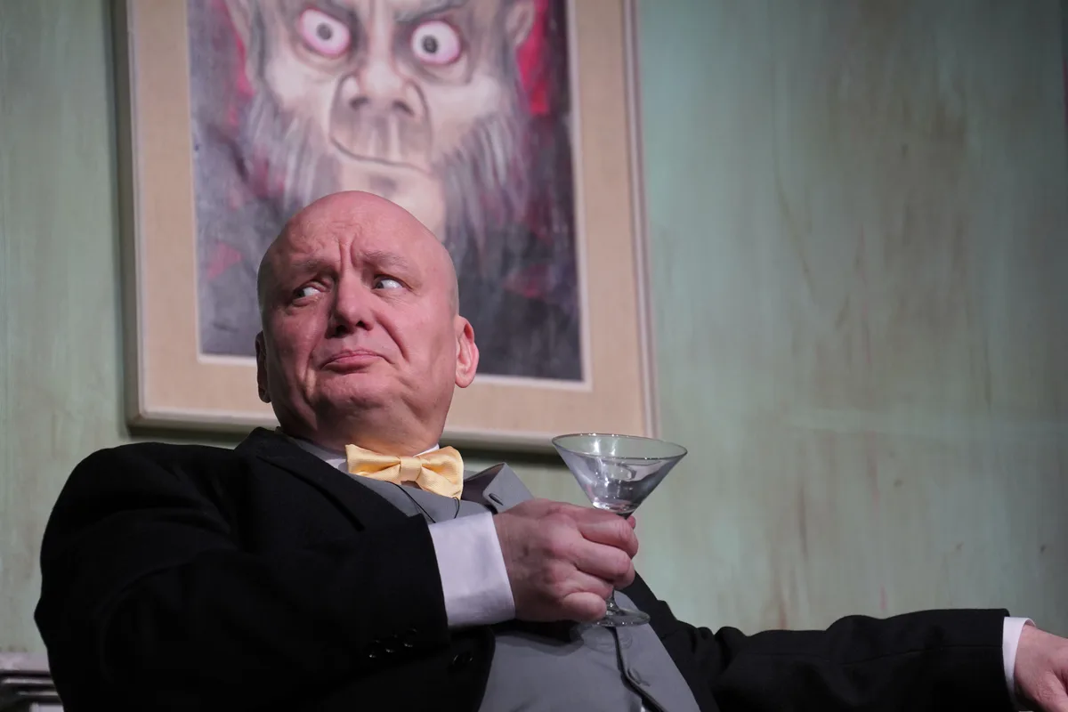 Ein Mann mit Smoking hält ein Martini-Glas.