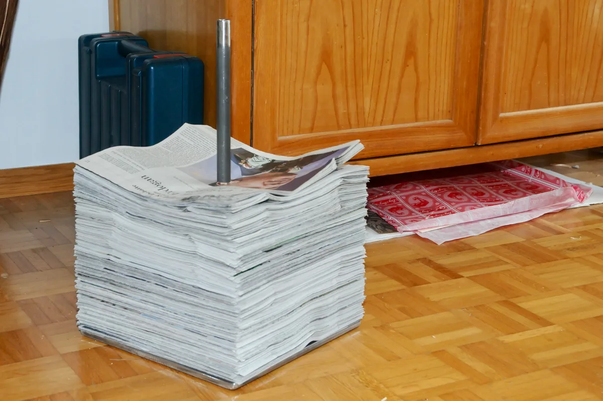 Man sieht einen Zeitungsstapel auf einer Metallstange aufgespiesst.