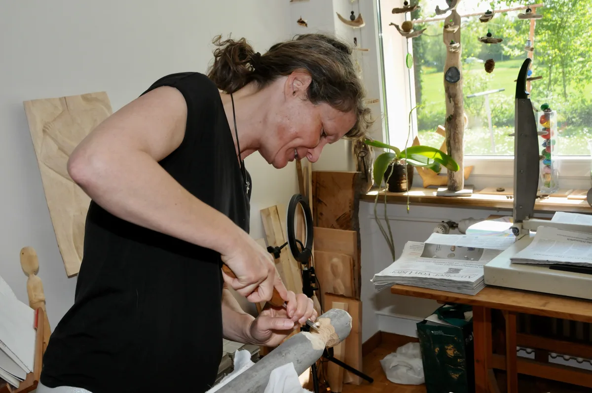 Man sieht Corinne Frauchiger beim Holzschnitzen.