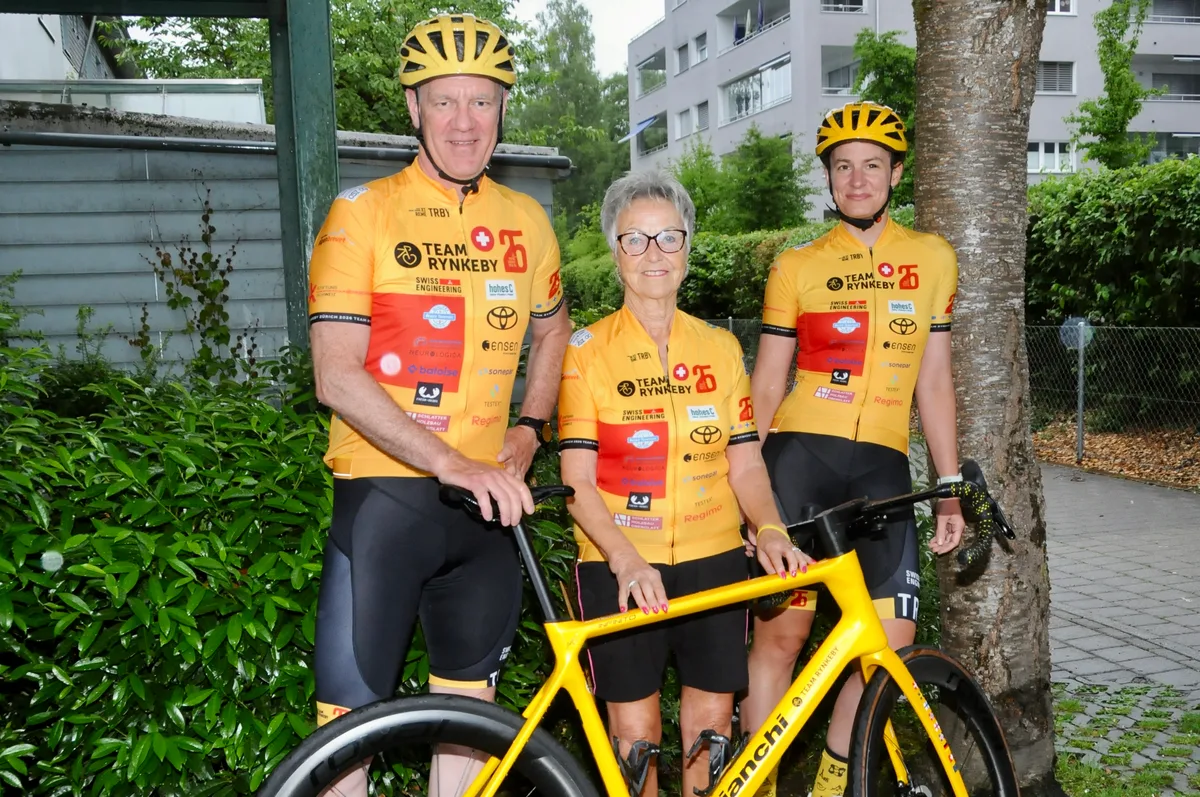 Marco Dietiker, Anni Reichle (Mitte) und Manu Weber freuen sich auf die Fahrt nach Paris. Zwei Frauen und ein Mann in gelber Velokleidung mit einem gelben Rennvelo.