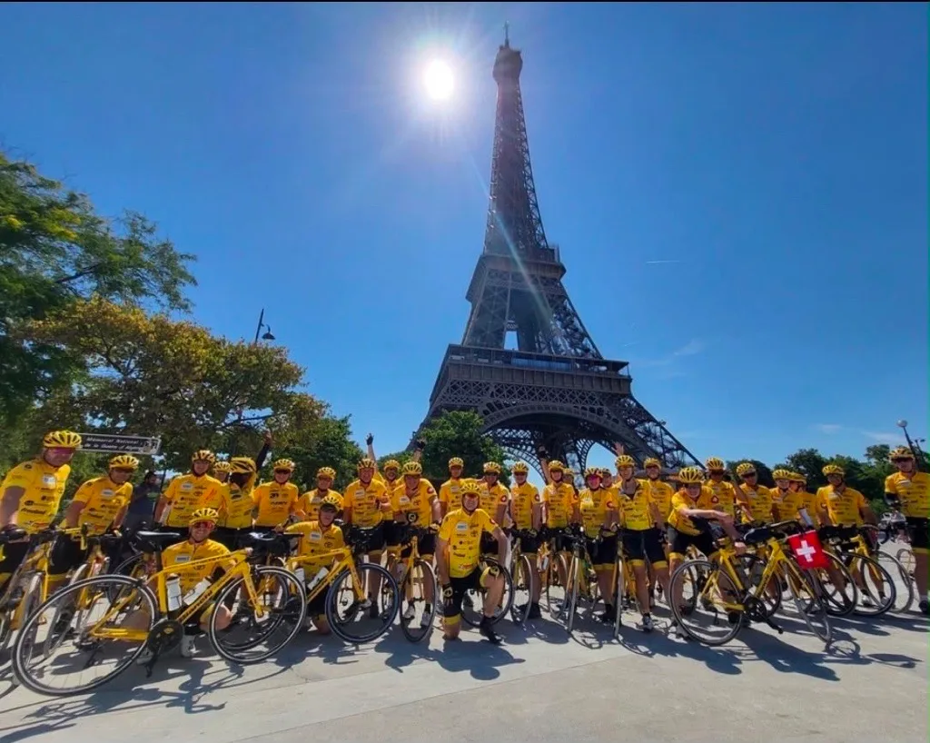 Das Ziel ist nach 1000 Kilometern erreicht: die Schweizer Delegation vor dem Eiffelturm in Paris. Man sieht viele Velofahrer in gelben Trikots vor dem Eiffelturm.