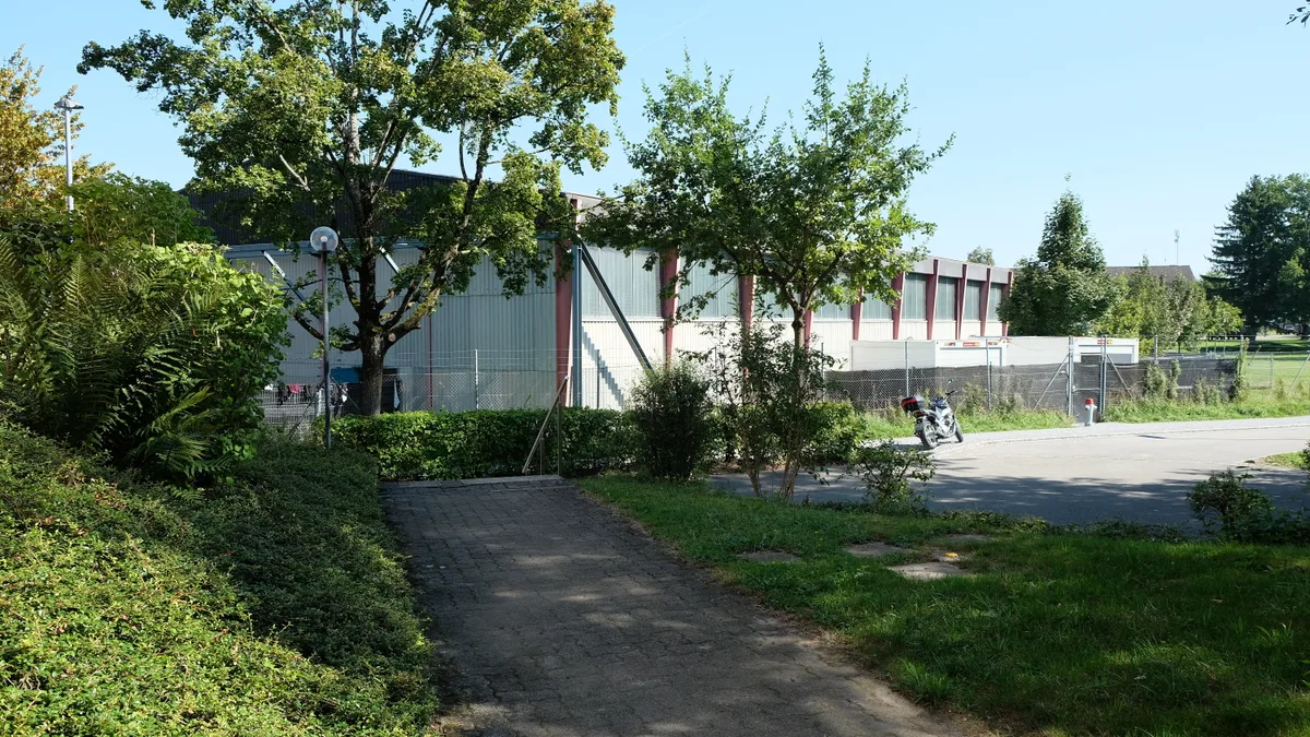Hier bringt der Bund temporär einen Teil der Asylsuchenden unter. (Archiv) Temporäres Bundesasylzentrum Dübendorf. Der Ausgang führt direkt in ein Wohnquartier.
