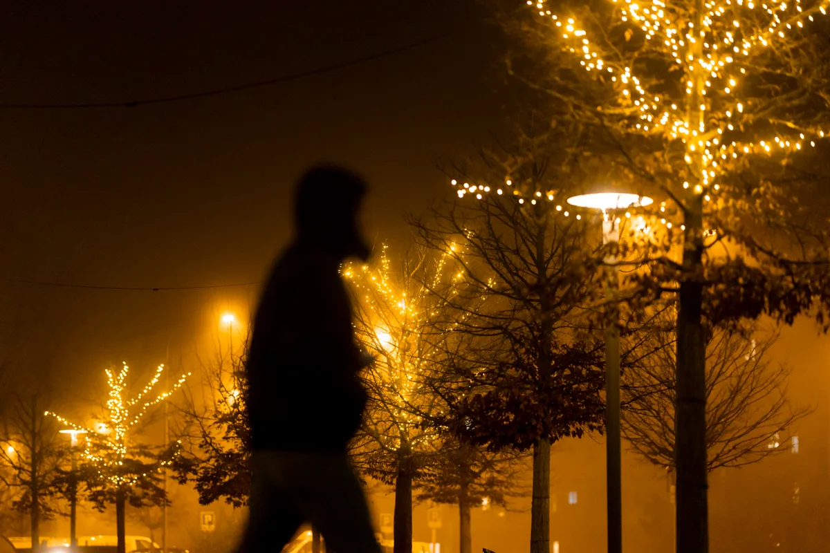 Passant vor beleuchteten Bäumen in Volketswil. Nächtliche Weihnachtsbeleuchtung.