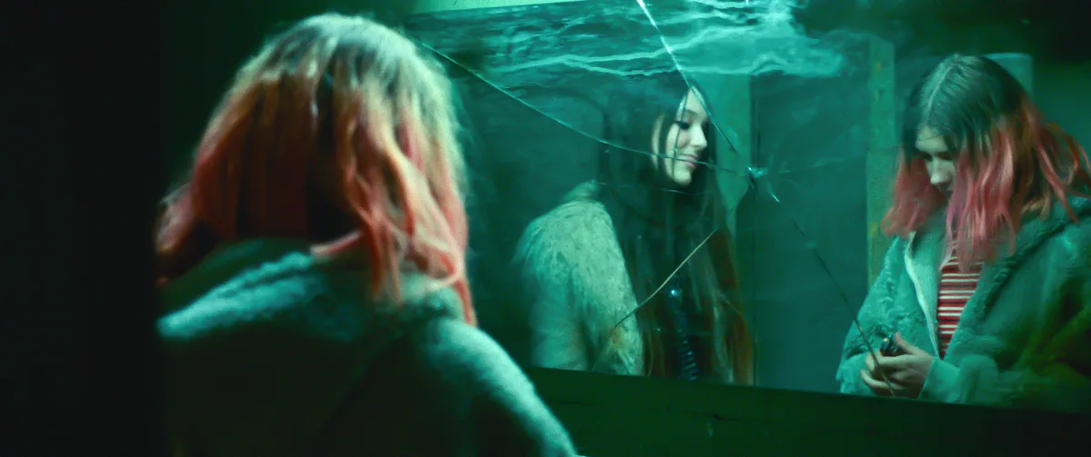 Lena und ein anderes Mädchen vor einem kaputten Spiegel.