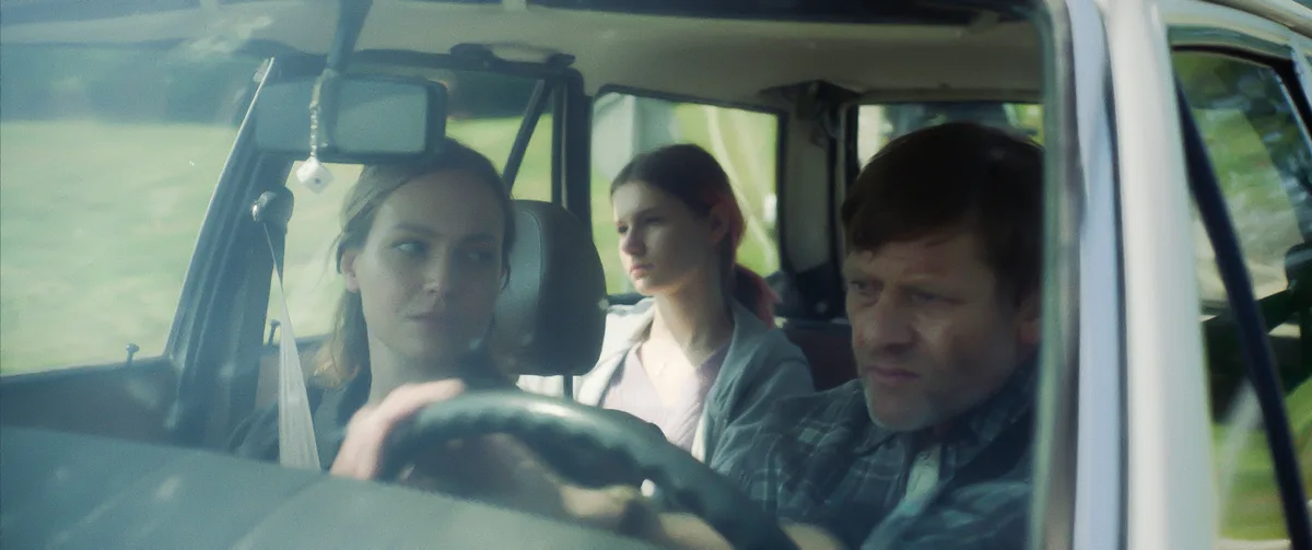 Die beiden Frauen sitzen mit einem Mann im Auto.