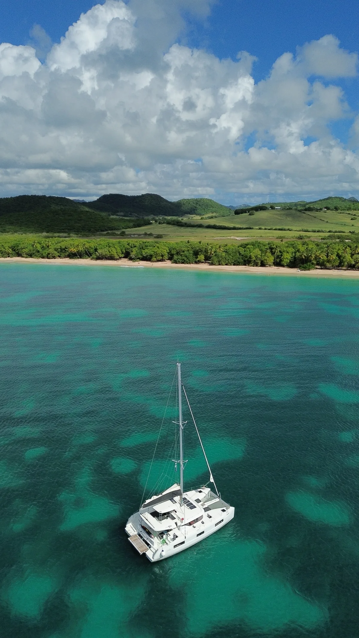 Nach drei Wochen auf hoher See legt das Team vor der karibischen Küste an. Vogelperspektive auf den Katamaran vor einer karibischen Insel.