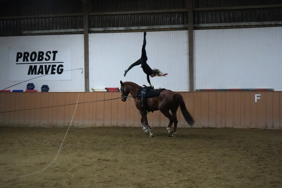 Leonie Linsbichler macht den einhändigen Handstand auf einem galoppierenden Pferd.