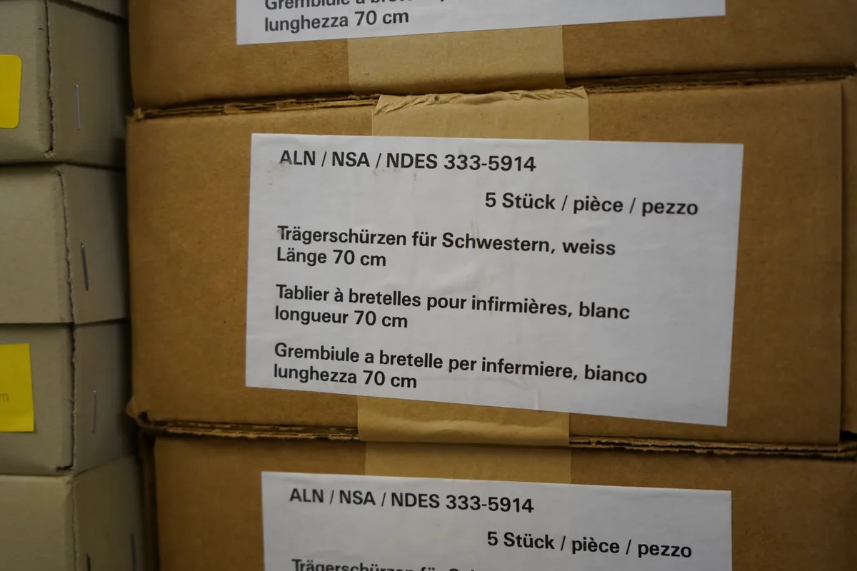 Eine Kiste ist mit «Trägerschürzen für Schwestern» beschriftet.