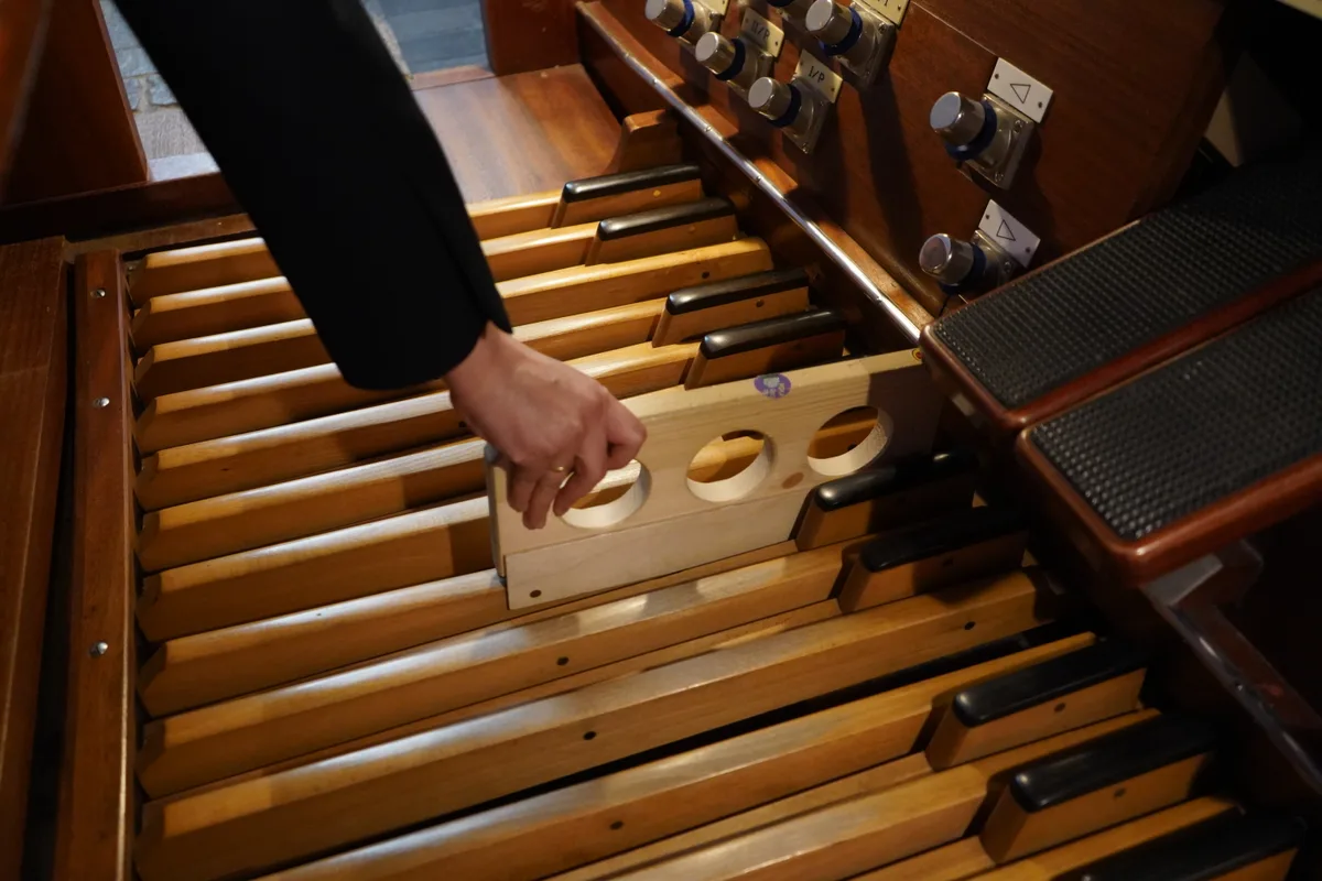 Yun Zaunmayr steckt ein Stück Holz auf ein Pedal der Orgel.