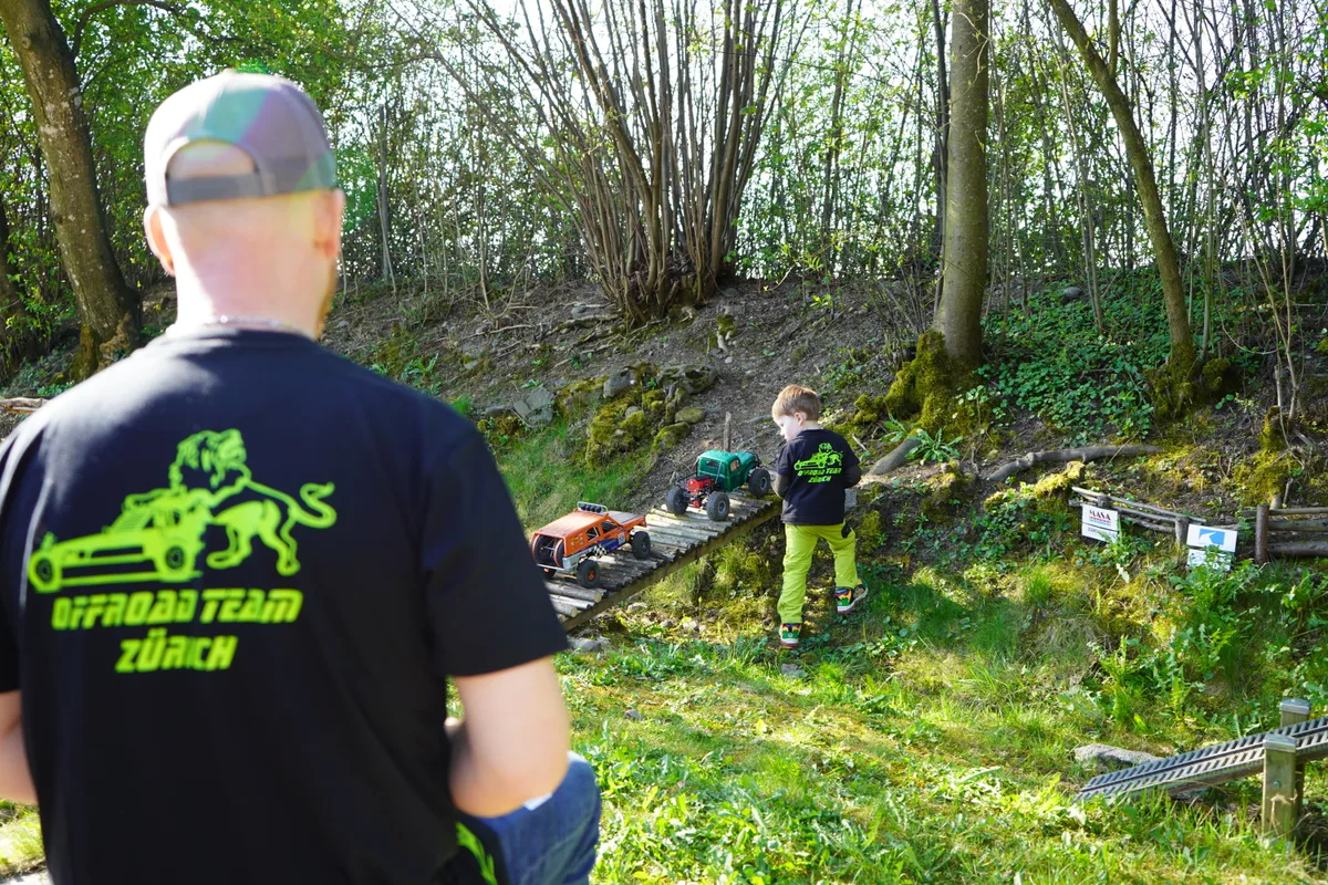 Vater und Sohn fahren zwei Modellautos auf einem Parcours.