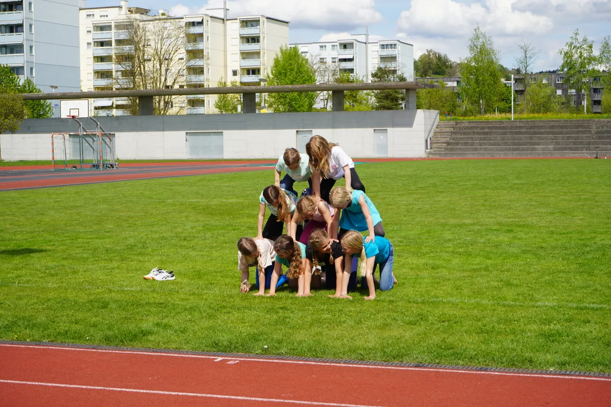 Zehn Mädchen bilden eine Pyramide auf dem Rasen.