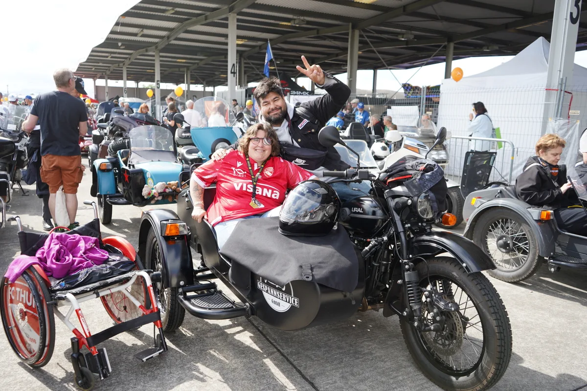 Eine Frau und ein Mann posieren auf einem Motorrad mit einem Seitenwagen.