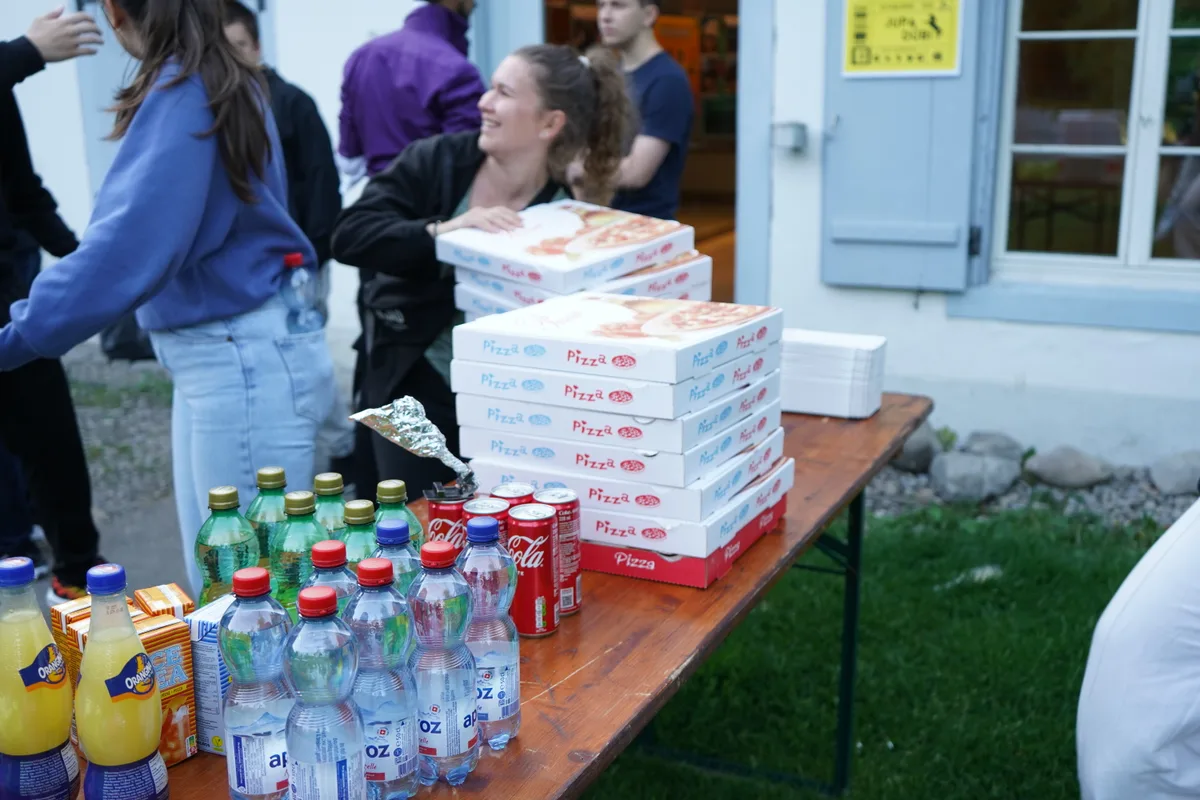 Auf einem Festtisch stapeln sich Pizzaschachteln und Getränke.