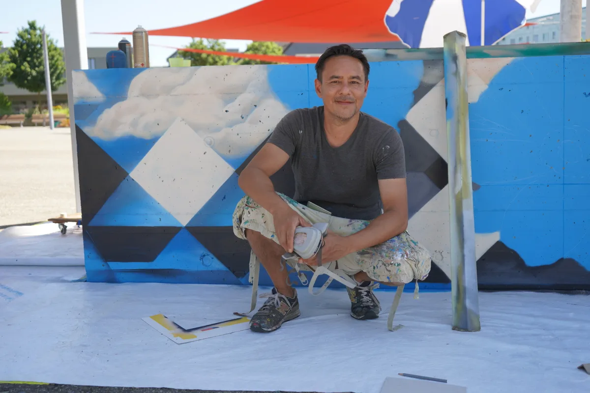Alex Hohl kniet vor seiner Streetart.