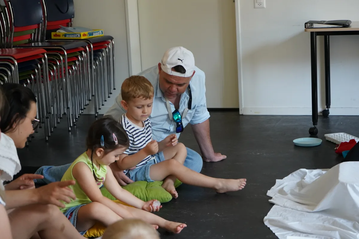 Zwei Eltern und ihre Kinder sitzen auf dem Boden.