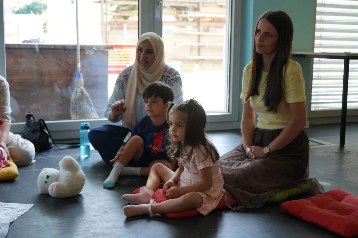 Zwei Mütter und ihre Kinder sitzen auf dem Boden.