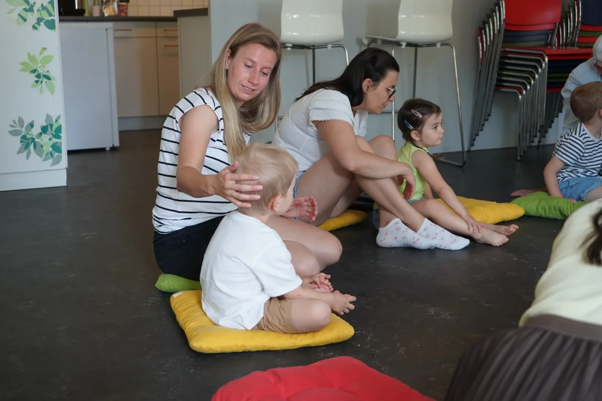 Zwei Mütter und ihre Kinder sitzen auf dem Boden.