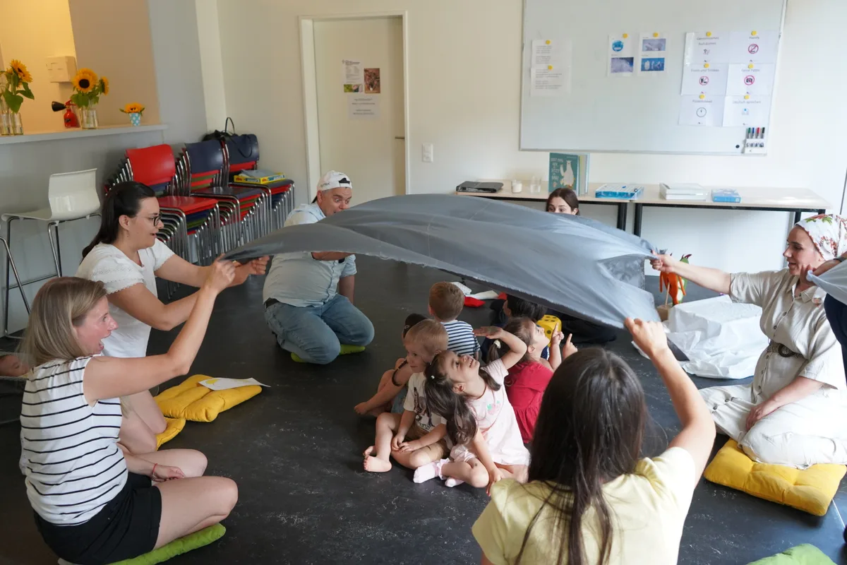 Die Eltern spannen ein Tuch über die Kinder.