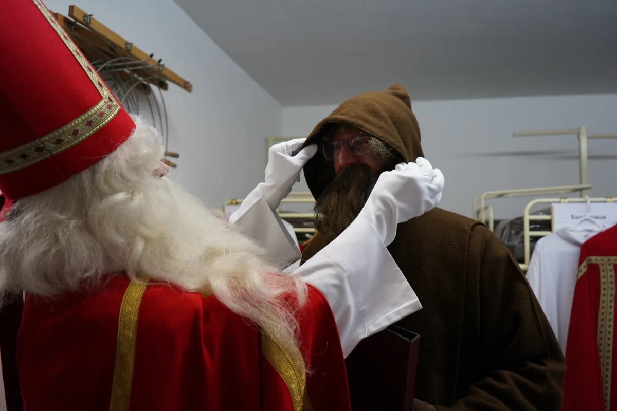 Der Samichlaus richtet die Kapuze des Schmutzli.