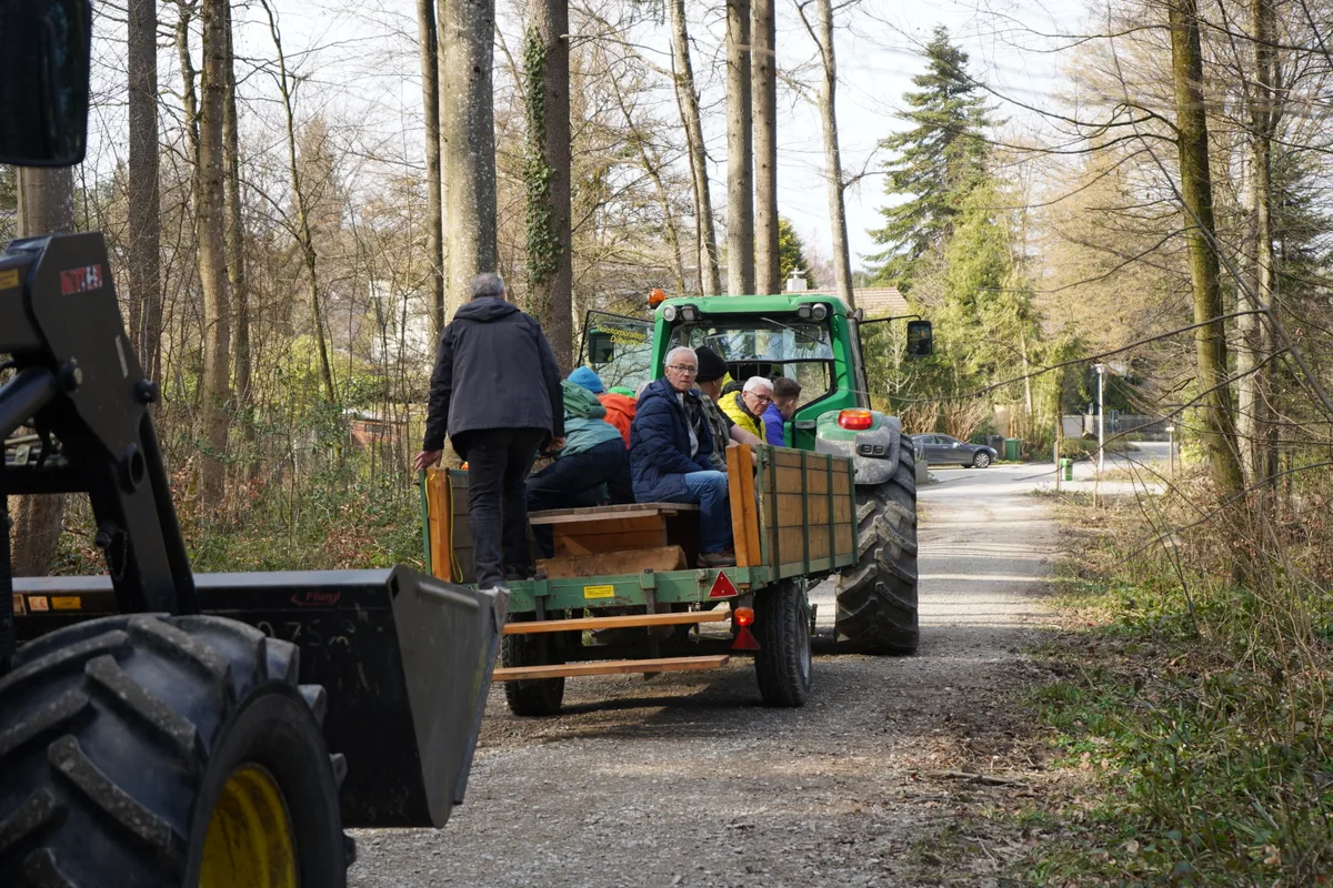 Mehrere Männer sitzen auf einem Anhänger.