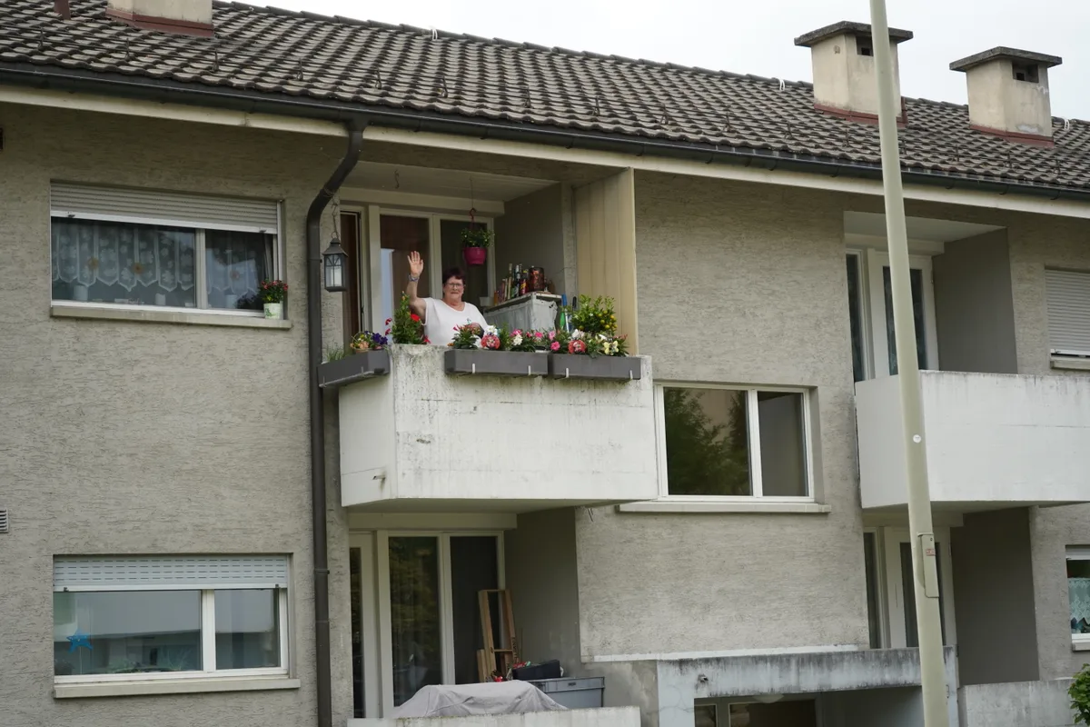 Eine winkende Frau auf dem Balkon.