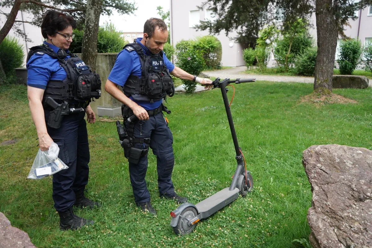 Zwei Polizisten halten einen E-Scooter.