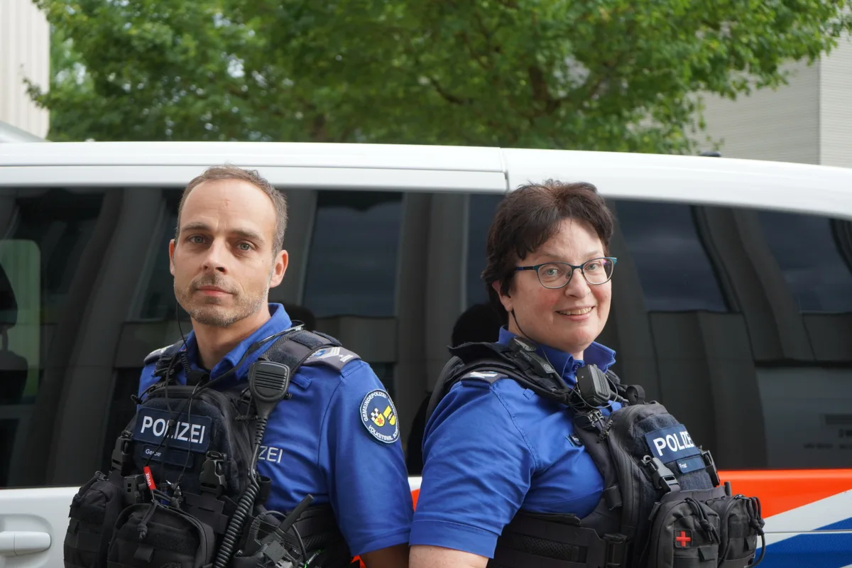 Zwei Polizisten vor einem Auto.