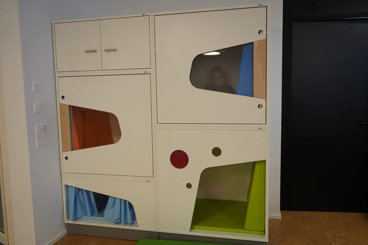 Ein Mädchen in einem Holzkubus.
