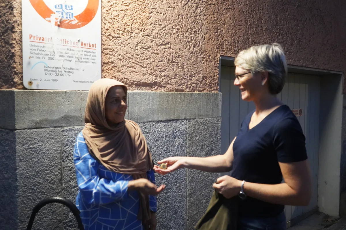 Eine Frau übergibt einer Bezügerin ein Los.