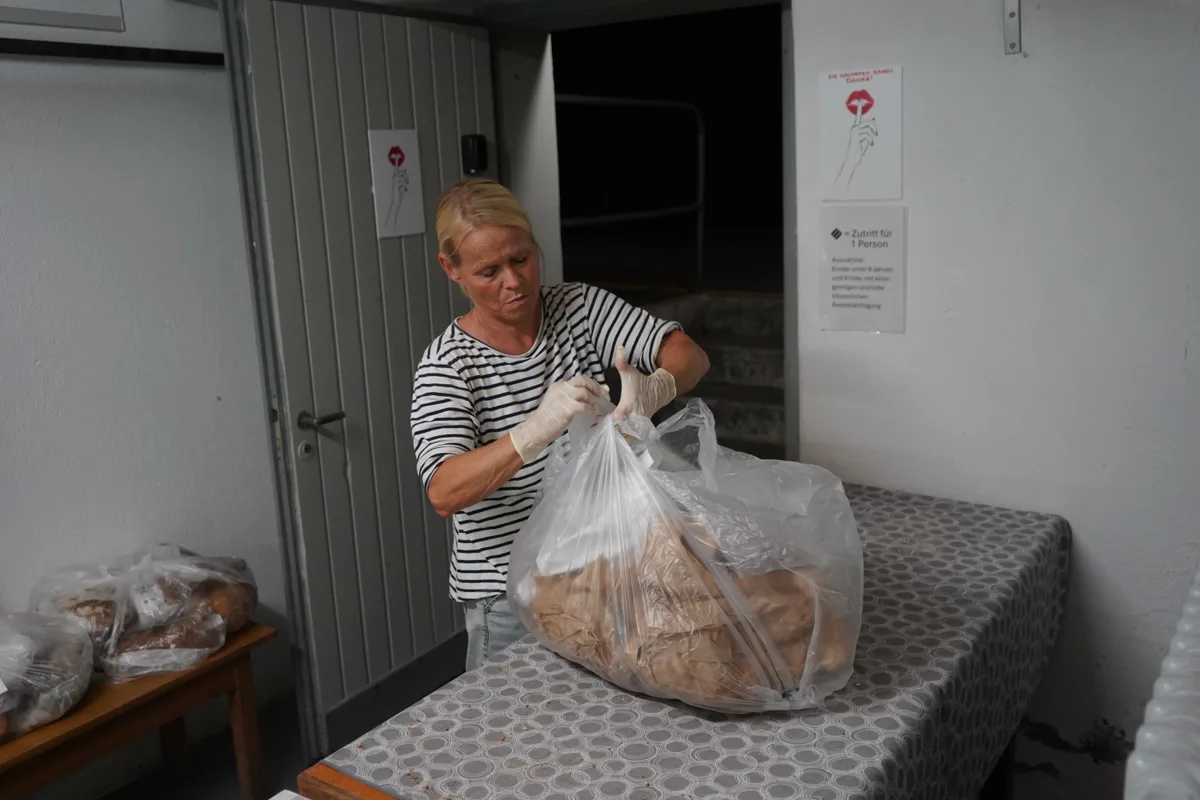 Eine Frau knöpft einen Plastiksack zu.